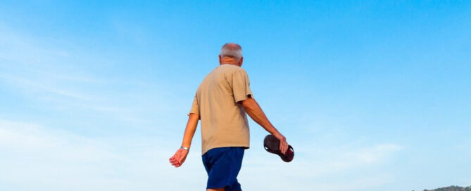 old man walking at the beach