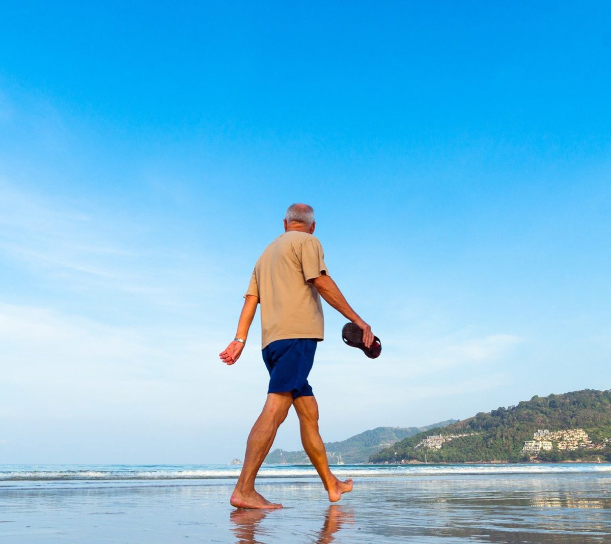 old man walking at the beach